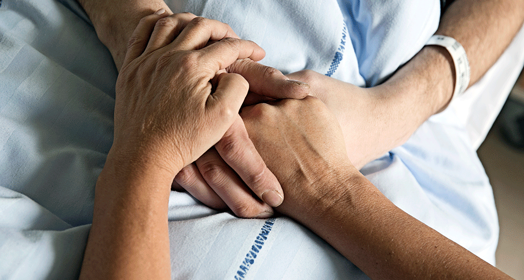 To par hænder, der holder hinanden i en hospitalsseng